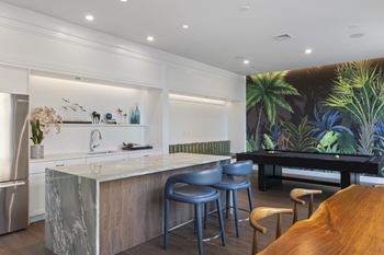 A kitchen with a marble island and blue chairs.